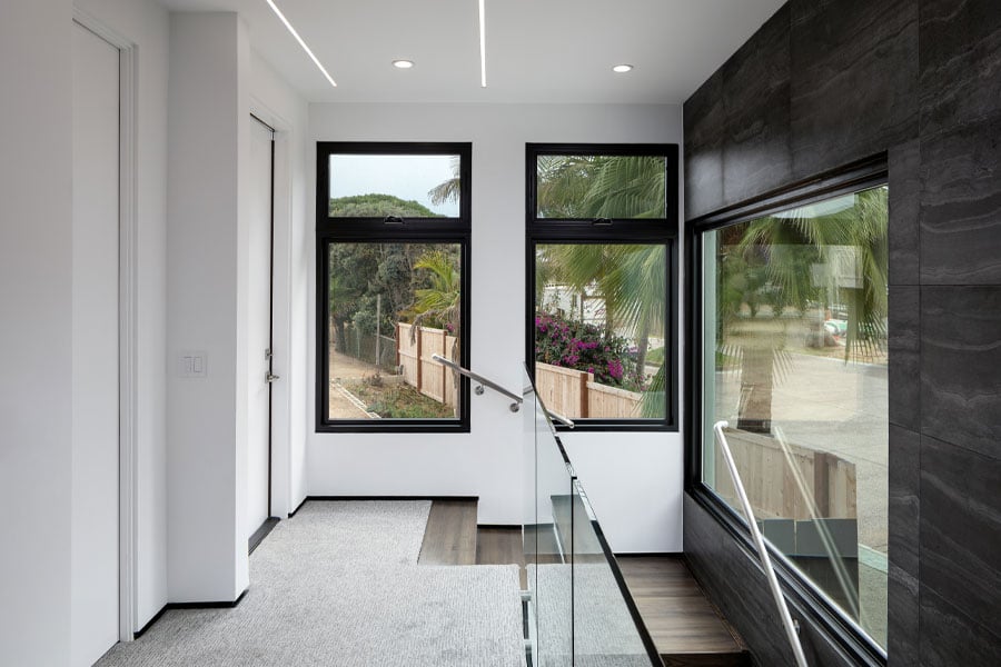 Picture and awning windows are combined in two different openings at the top of a staircase where they serve to bring in lots of natural light. 