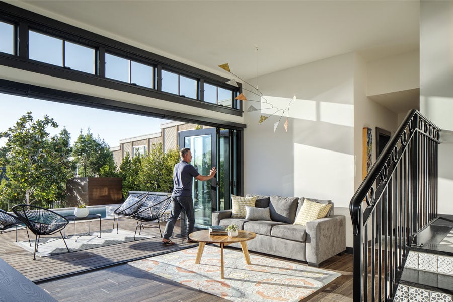 A bifolding door is opened to connect a family room with the raised deck outside