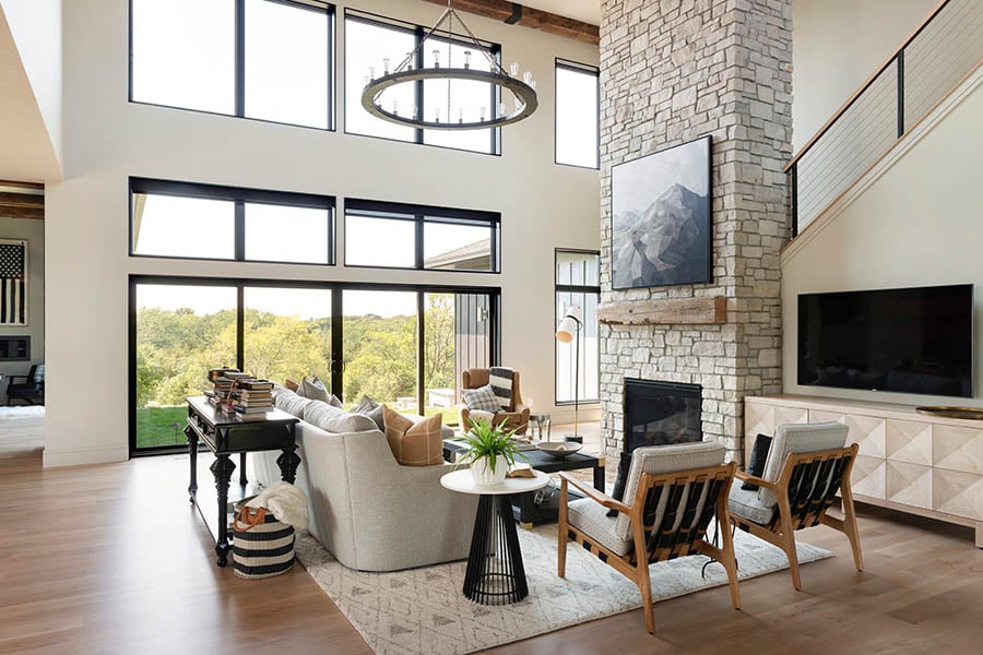 A two-story living room with stunning views is connected to the outdoors via a 4-panel sliding patio door with transoms above and a bank of picture windows near the ceiling