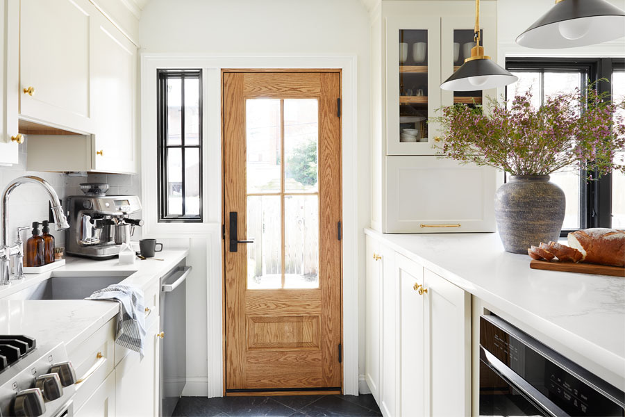 An oak front door with large windows lets light into a remodeled kitchen.