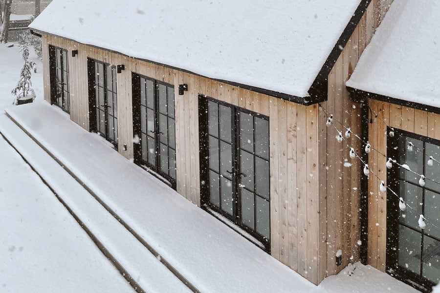 exterior of wood barn with black framed Andersen windows in winter