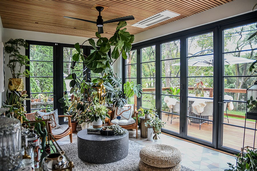 The east and south walls of Hilton Carter’s renovated sunroom feature glass walls thanks to the floor-to-ceiling Andersen windows and Folding Outswing doors 