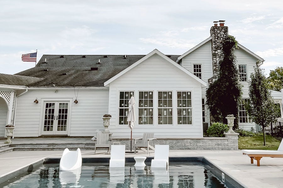 Liz Marie Galvan’s farmhouse viewed from the back where a new addition featuring a primary suite with Andersen windows sunroom faces the swimming pool  