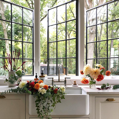 Large, black windows over kitchen sink filled with flowers