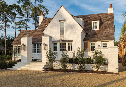 White windows with colonial grilles help complete the look of this traditional home built of white painted brick and featuring a cedar shake roof.