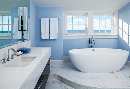 Blue bathroom with white windows over freestanding tub