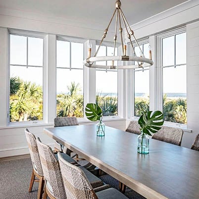 coastal dining room with large table and Andersen white framed windows
