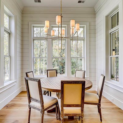 white traditional dining room with round table and white framed Andersen windows