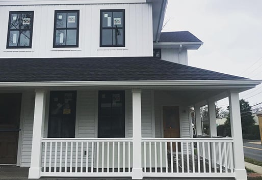 closeup of white farmhouse porch with black large grid Andersen windows