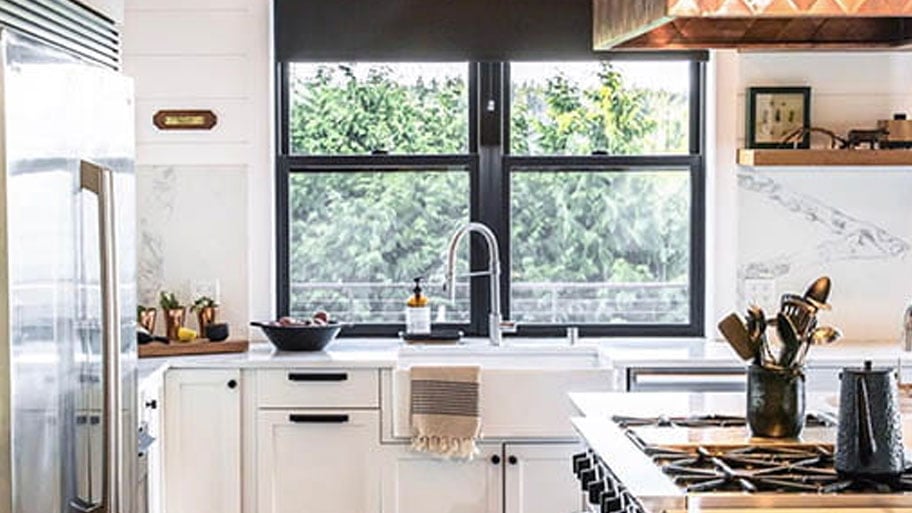 interior view of white kitchen with black frames andersen windows used as backsplash