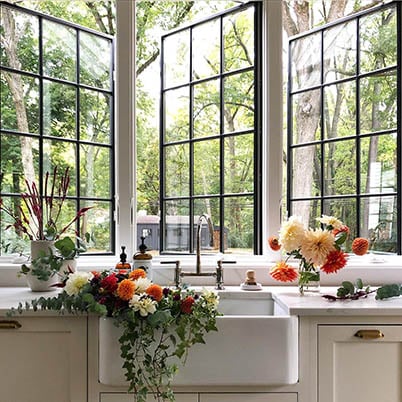 Black casement windows that open outwards with colonial grilles above kitchen sink to help fresh air clear away smoke, cooking smells and other indoor pollutants that commonly occur in kitchens.