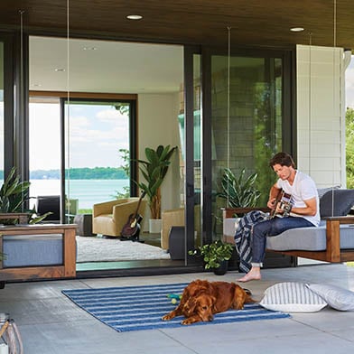 man playing guitar with dog outdoor patio on modern home with andersen doors