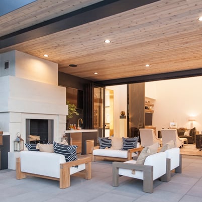 Modern outdoor living space with white furniture and a fireplace.