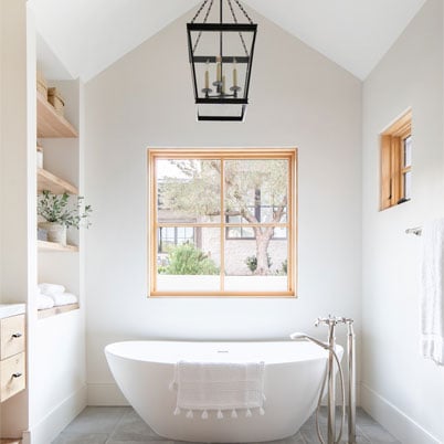 bathroom with focus on white modern tub and andersen light wood framed e series window with panes