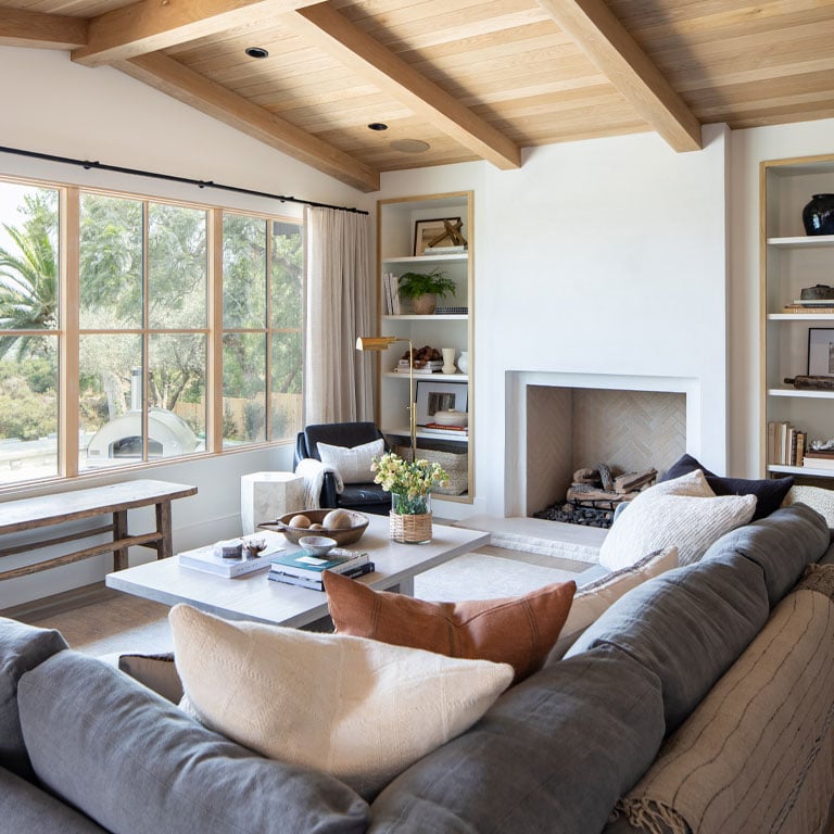 white family room with gray couch. light wood ceiling and light wood framed andersen e series windows with panes
