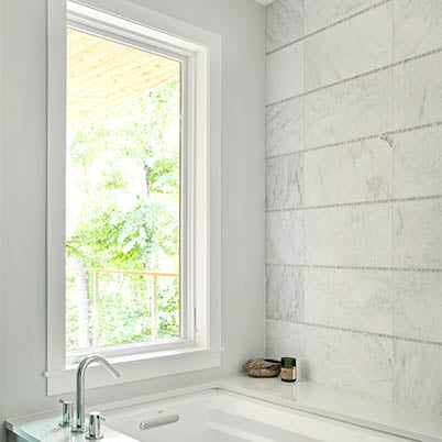Modern white bathroom with a white Andersen window with white trim.