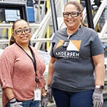 2 andersen employees in front of machinery