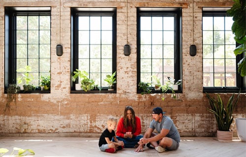 interior brick building with a series windows, family sitting on floor