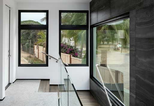 Interior of home by top of stairway with black Andersen casement, awning, and picture windows.