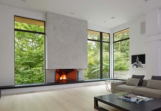Modern, open living room with e-series picture windows beside a fireplace