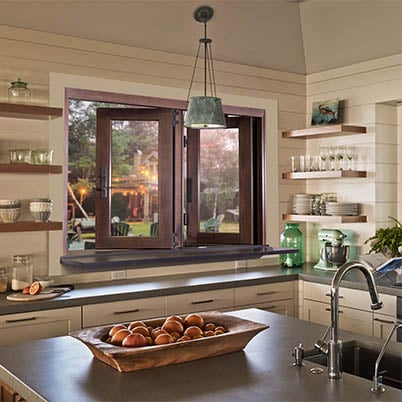Brown Andersen pass-through folding window in tan kitchen with fruit on counter near sink
