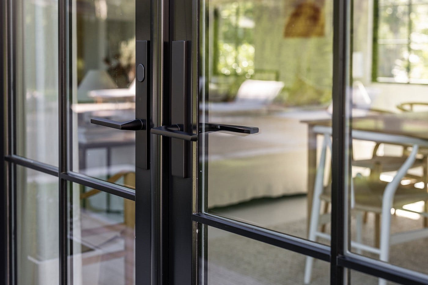 A closeup shot from the exterior featuring a black E-Series Hinged Patio Door with Baldwin® designer hardware.