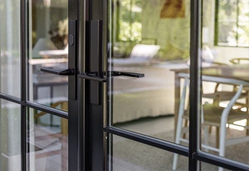 A closeup shot from the exterior featuring a black E-Series Hinged Patio Door with Baldwin® designer hardware.